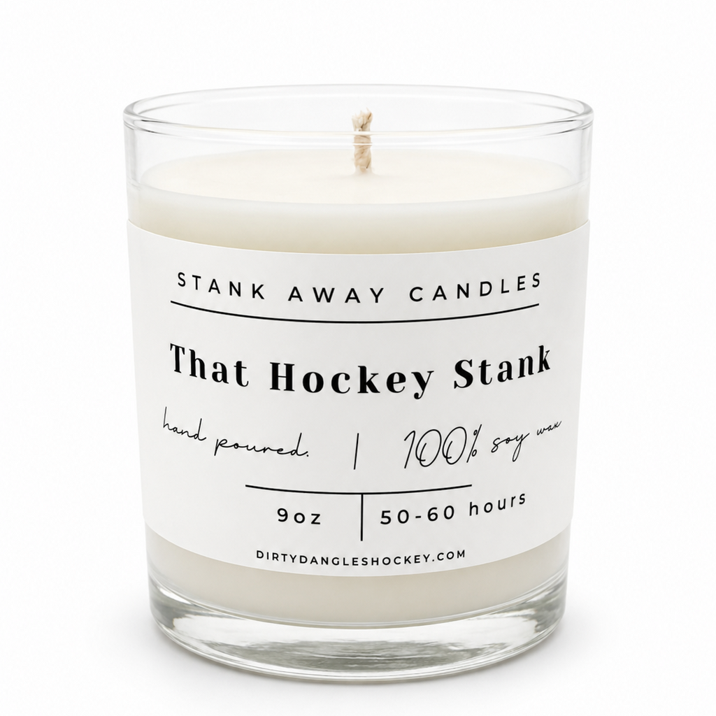 3 candles on a hockey net with hockey sticks and a hockey puck in the background. Because hockey gear. Because my kid plays hockey. That hockey stank.