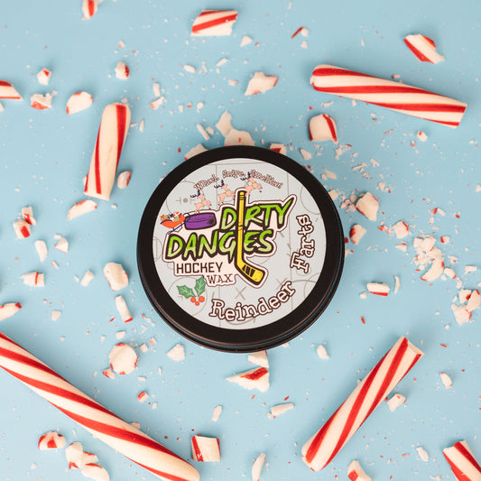 A tin of dirty dangles reindeer farts holiday hockey stick wax on a blue background with candy canes