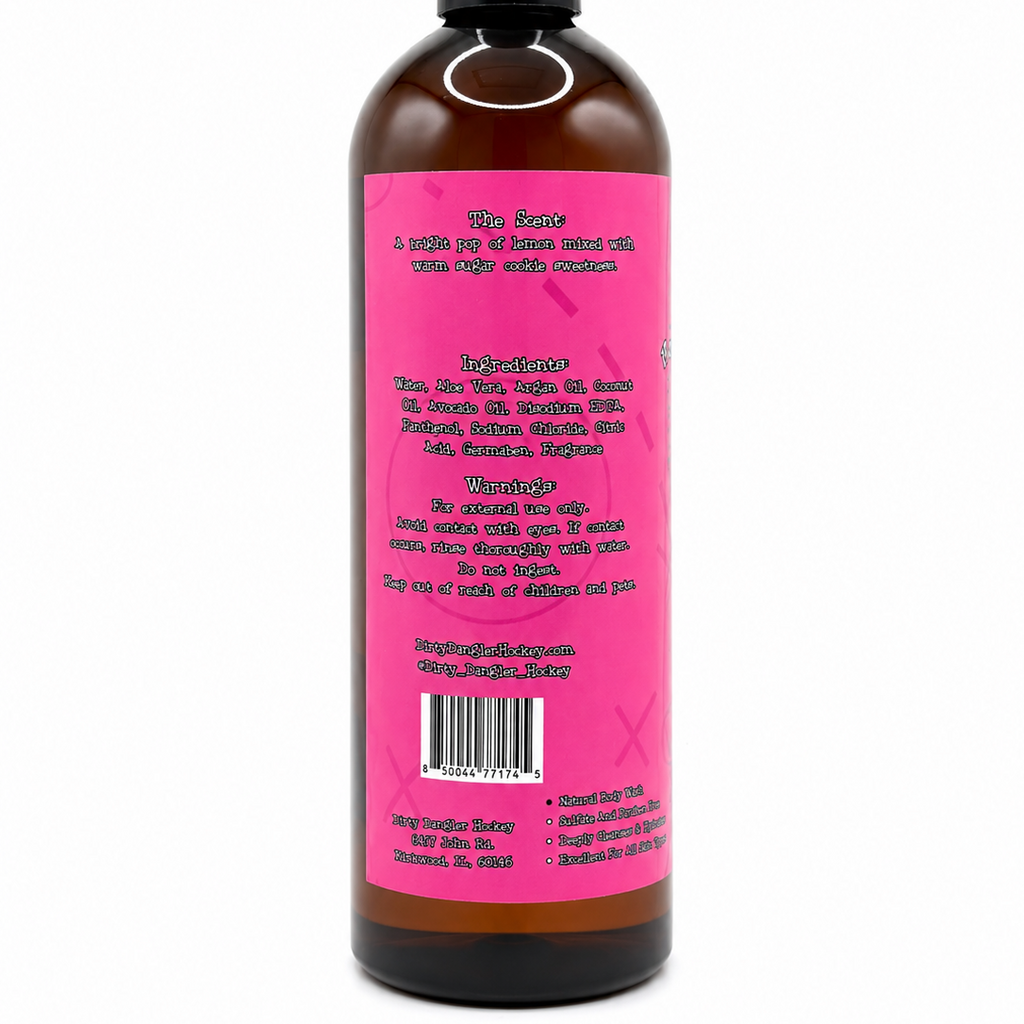 A dark amber bottle of dirty dangles girls hockey body wash goal digger lemon sugar cookie scent shown from the back, featuring a bright pink label with black text and a black flip-top cap, isolated on a white background.