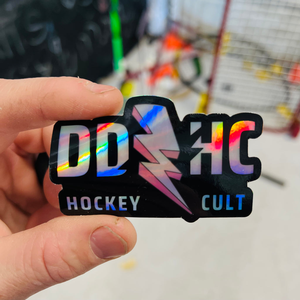 a hand holding a holographic dirty dangles hockey sticker
