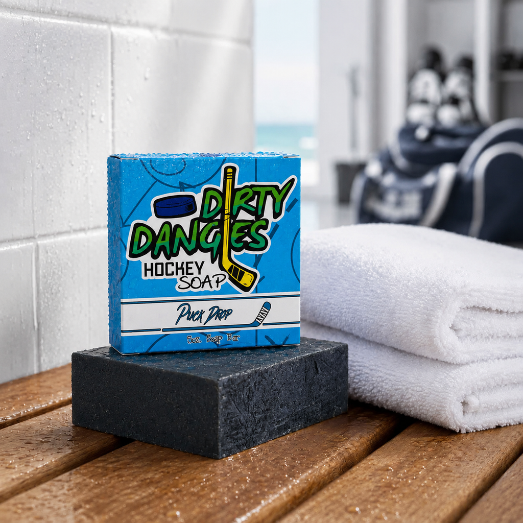 puck drop pin, orange and vanilla scented hockey soap bar on a bench in a locker room with a white towel and hockey gear