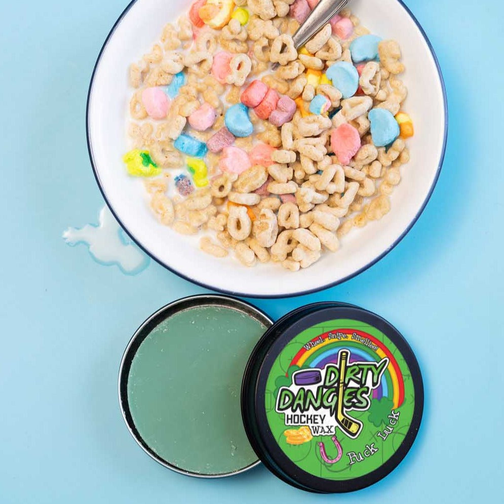 A tin of Dirty Dangles Hockey Wax Puck Luck St Patrick's Day scent on a blue background with lucky breakfast cereal