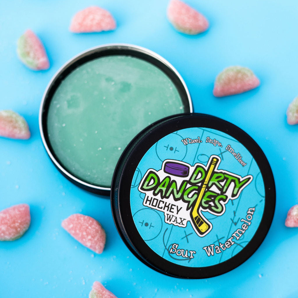 An open tin of dirty dangles sour watermelon hockey stick wax on a blue background with sour watermelon candies