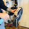 A man spraying an ice skate with a bottle of Stank Fighter hockey gear deodorizing spray