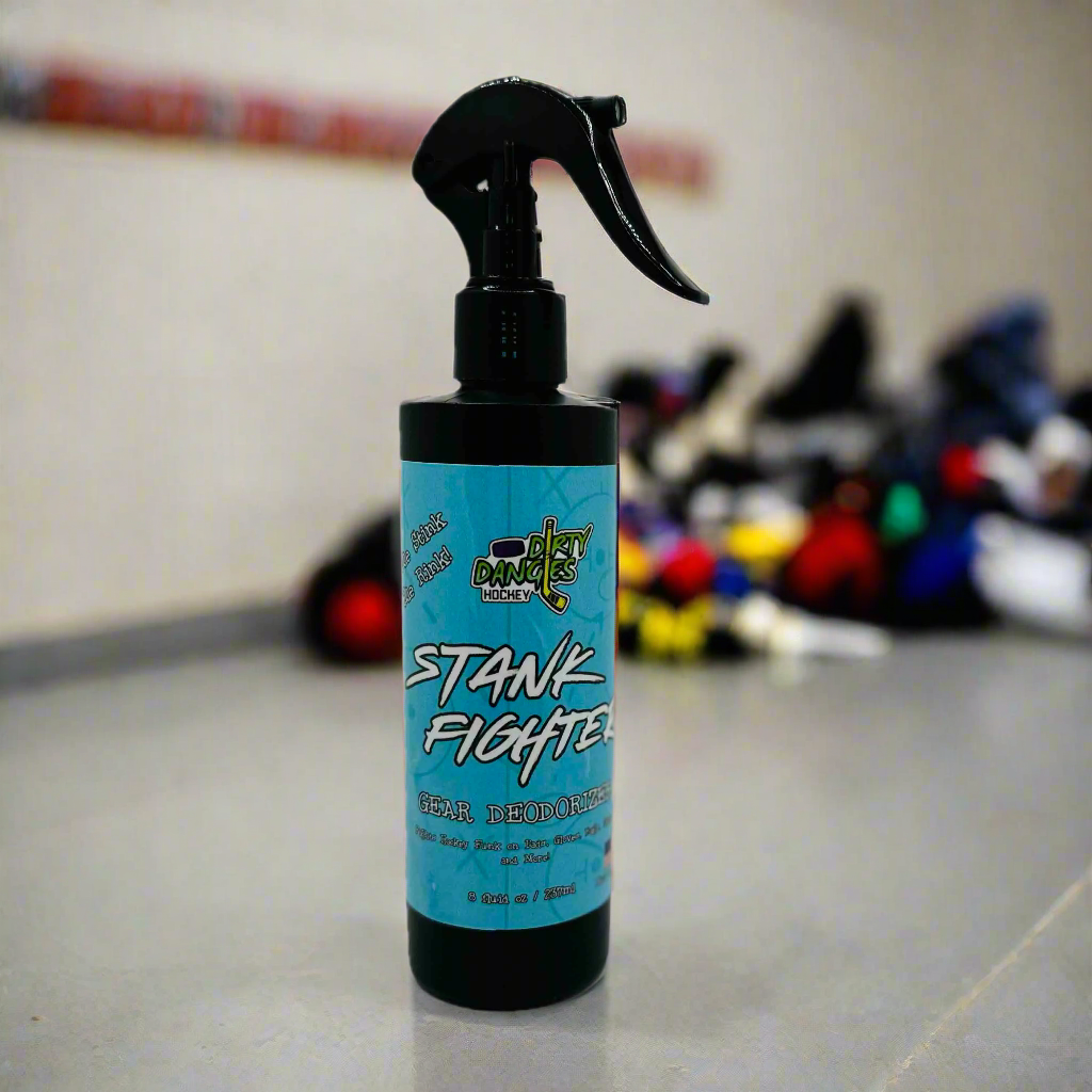 A blue bottle of stank fighter hockey gear deodorizing spray in a locker room with dirty hockey gear in the background