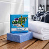 The Michigan hockey soap bar and box on a wet locker room bench beside folded white towels with hockey gear in the background.