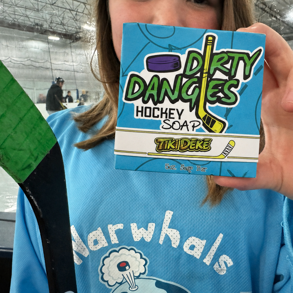 A girl hockey player holding a bar of tiki deke tropical coconut hockey soap inside an ice rink