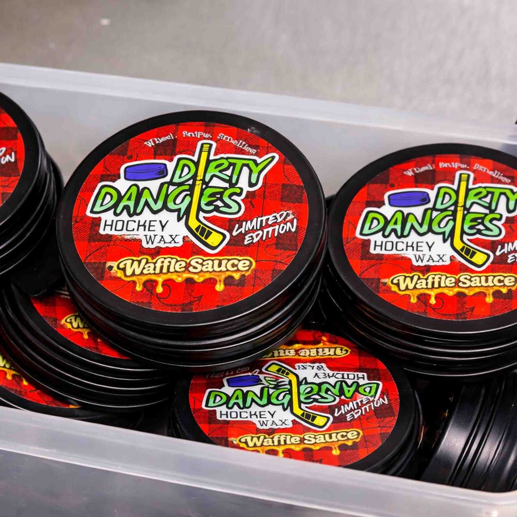 Multiple containers of Dirty Dangles Waffle Sauce scented hockey wax with red and black labels.