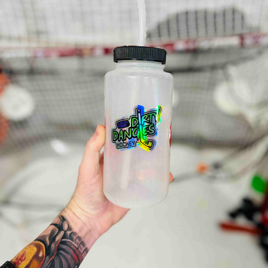 A hand holds a water bottle with a dirty dangles hockey logo sticker on it. Dirty Dangles hockey