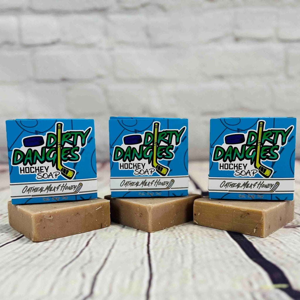 3 bars of dirty dangles oatmeal milk and honey scent soap against a wood and brick background. Dirty Dangles hockey soap.