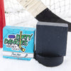 A black soap bar sits in the snow with a hockey goal, hockey puck and a hockey stick. Puck Drop scent