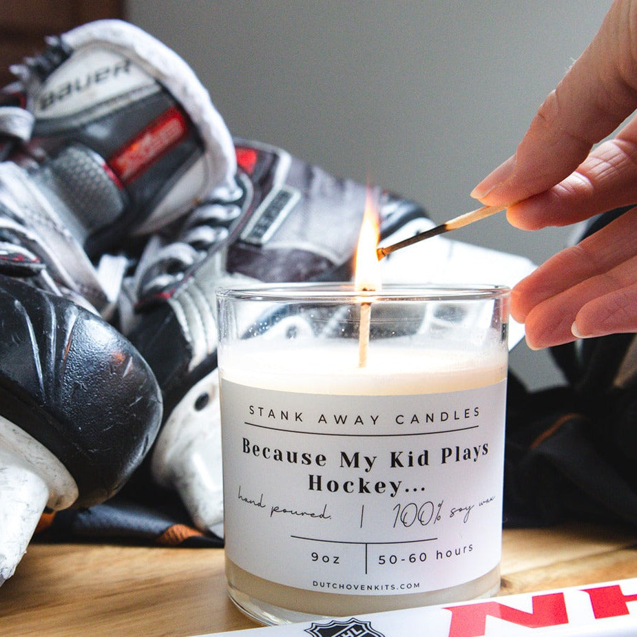 A white candle sits on a table with a pair of ice skates and a hockey stick. Because my kid plays hockey....
