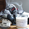A white candle sits on a table with a pair of ice skates and a hockey stick. That hockey stank.